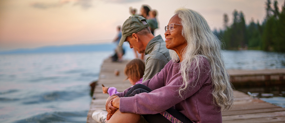 Family sitting on dock, smiling mother looking out across the water